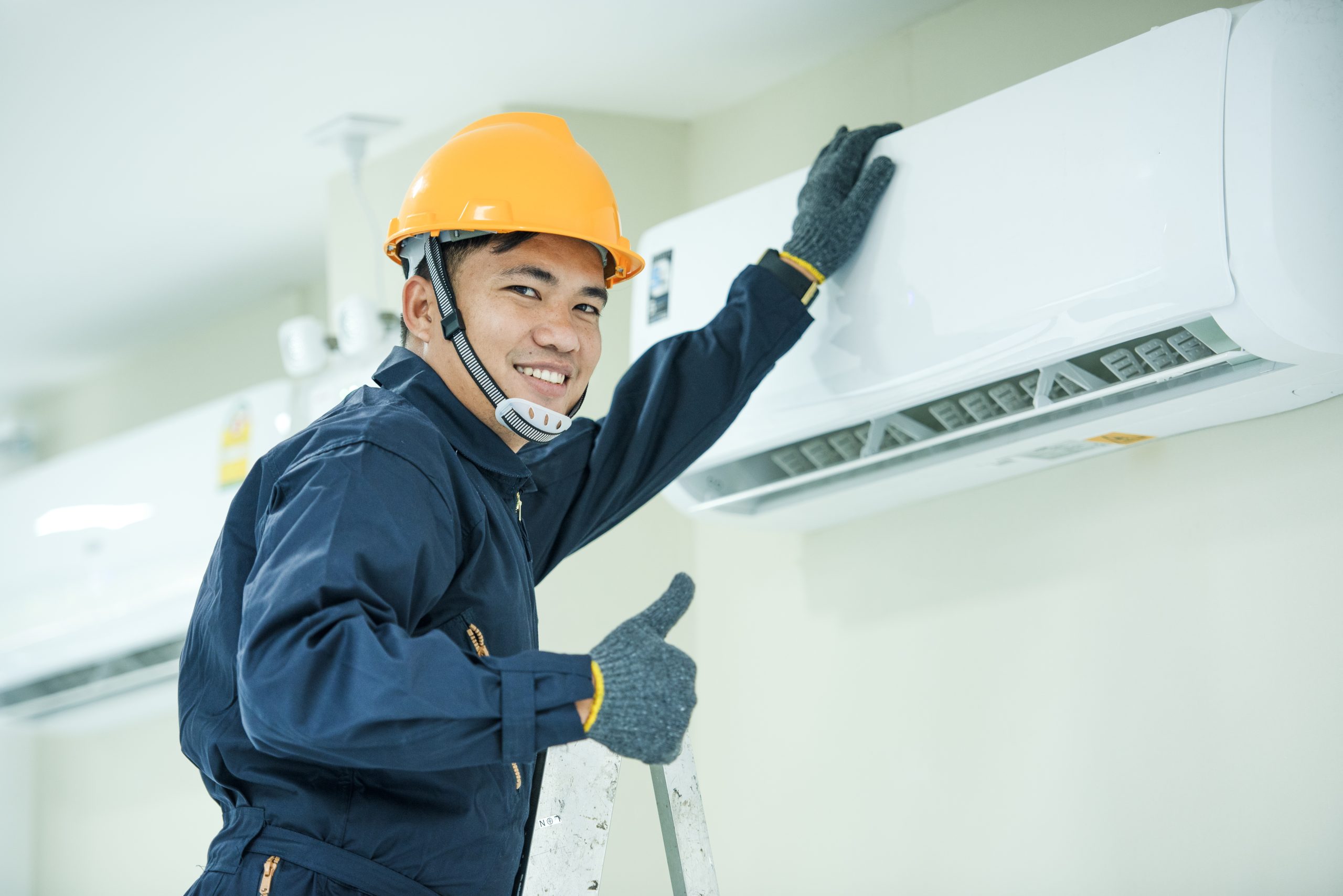 asian young technician service man wearing blue uniform checkingprofessional air conditioner installer maintaining modern indoor air conditioner space text scaled